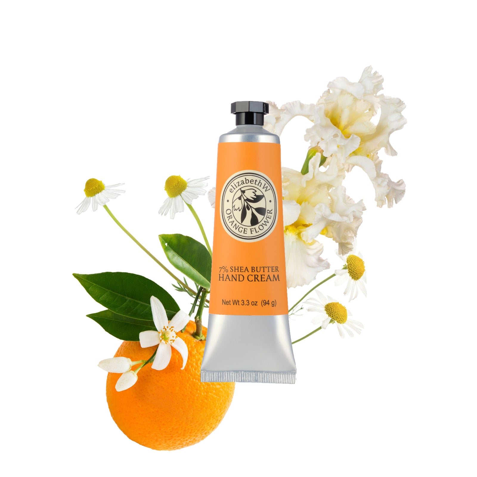 Fresh whole and sliced oranges arranged with green leaves and small white blossoms on a marble surface.