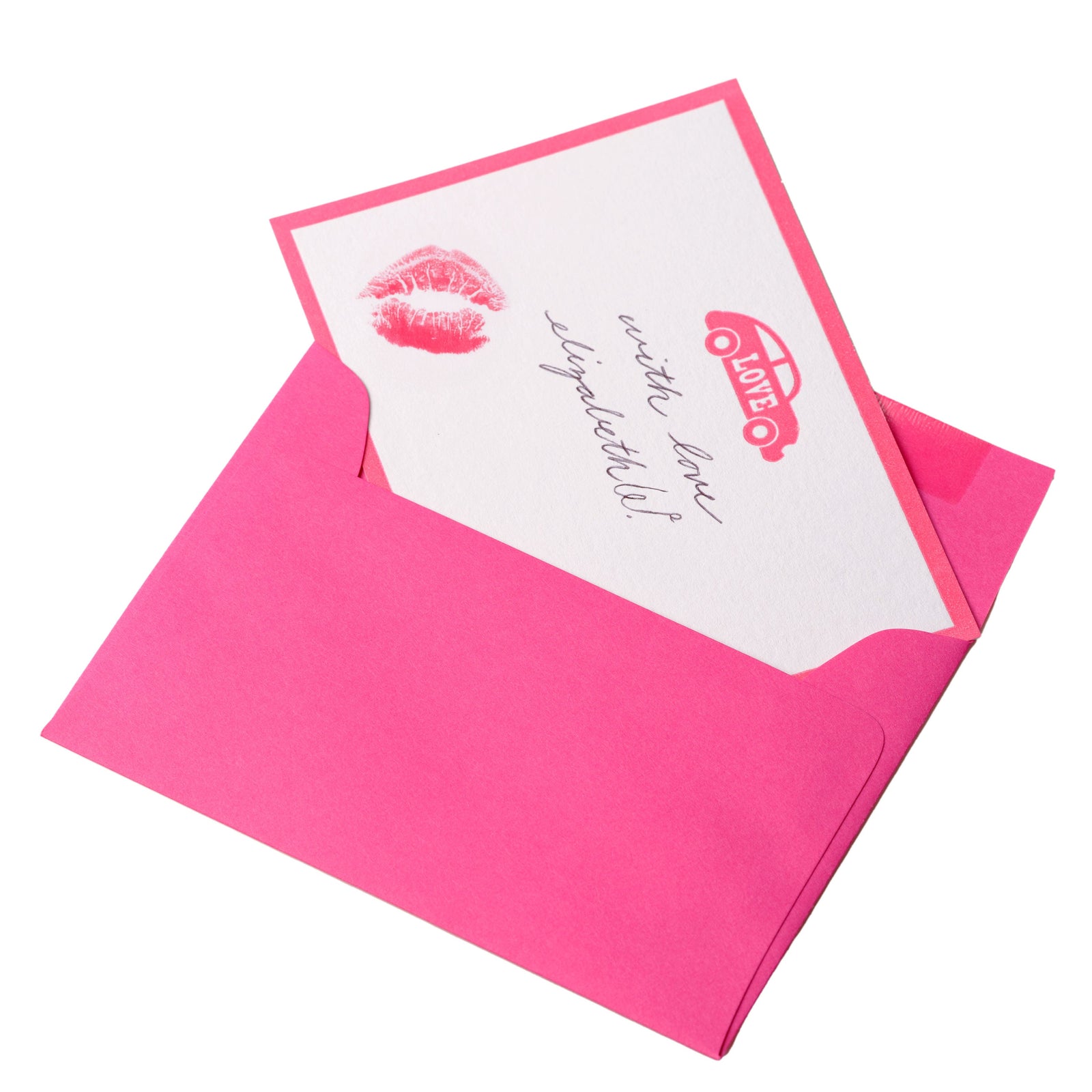 A pink envelope with a card inside, featuring the phrase "write love signatures!" Lipstick kiss mark and a heart with a car design printed in red.