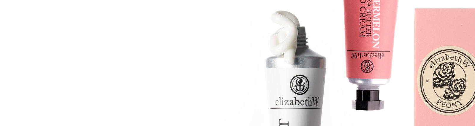 A close-up of a foamy pink shower gel bottle with a metallic pump. The label features cursive text and a decorative emblem.