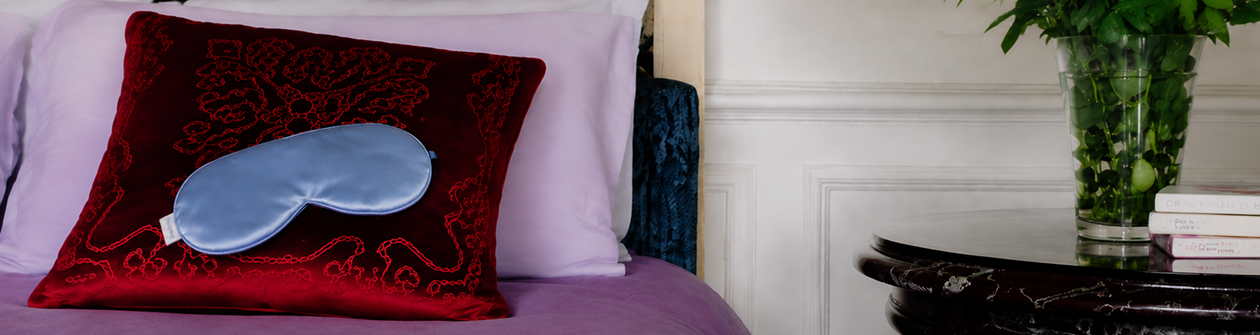 A light blue satin sleep mask lies on a shiny dark green tiled surface.