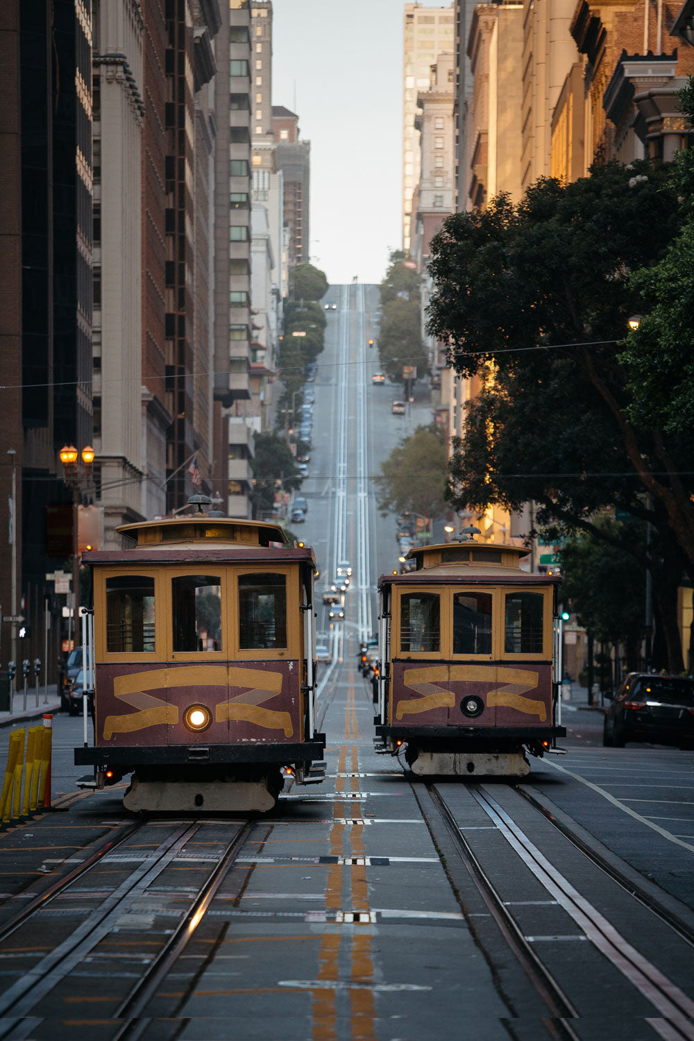 Two San Francisco cable cars side-by-side on a downtown avenue. 
