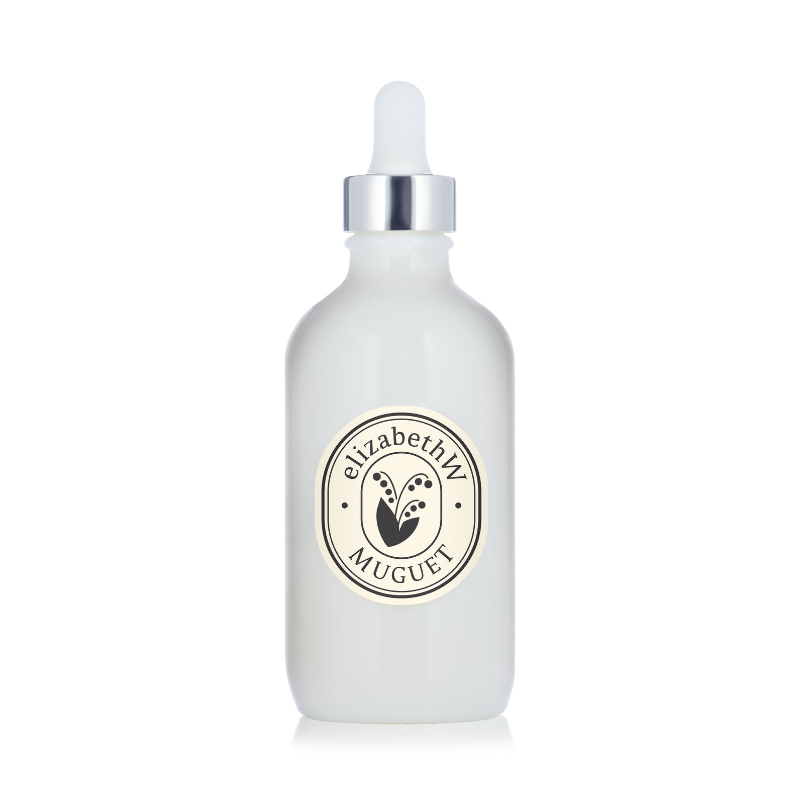 A sleek white dropper bottle with a silver cap and an "elizabethW Muguet" label is shown against a white background. Inside, the Muguet — Body Oil by elizabethW offers nourishing hydration for your skin, infused with the soft, floral scent of Muguet for a luxurious moisturizing experience.