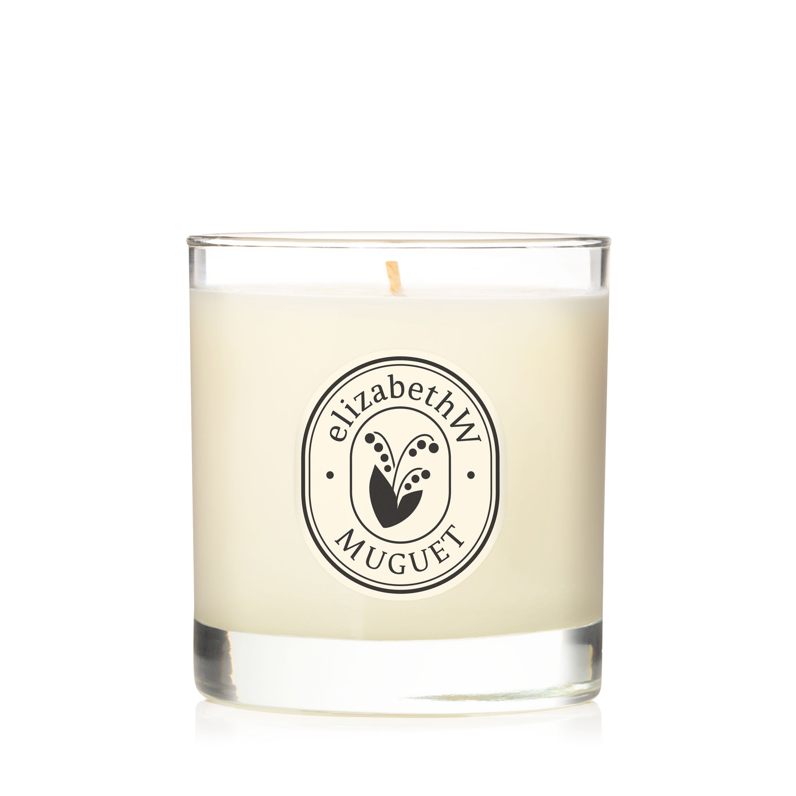 The elizabethW Muguet — Perfume Candle is a hand-poured soy wax candle in a clear glass jar with one wick, featuring a refined “elizabethW Muguet” label and elegant logo—ideal for adding perfect fragrance to any space.