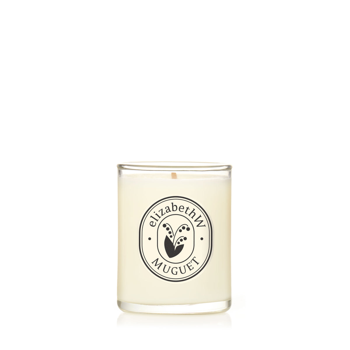 The elizabethW Muguet — Petite Perfume Candle is a hand-poured white scented candle in a clear glass holder with a black and white "elizabethW Muguet" label and lily of the valley design, made from renewable soy wax.