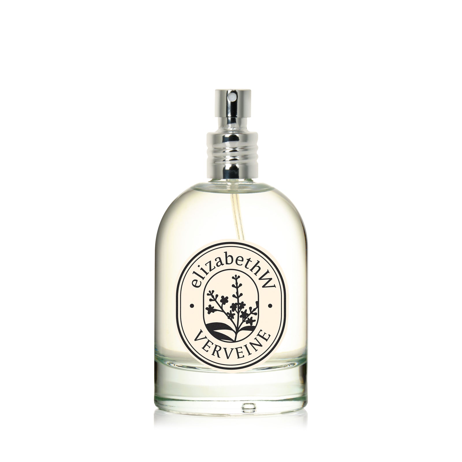 A clear glass bottle of elizabethW’s Verveine — Eau de Parfum features a silver spray top, labeled with a botanical design. It offers a fresh citrus and herbaceous scent.