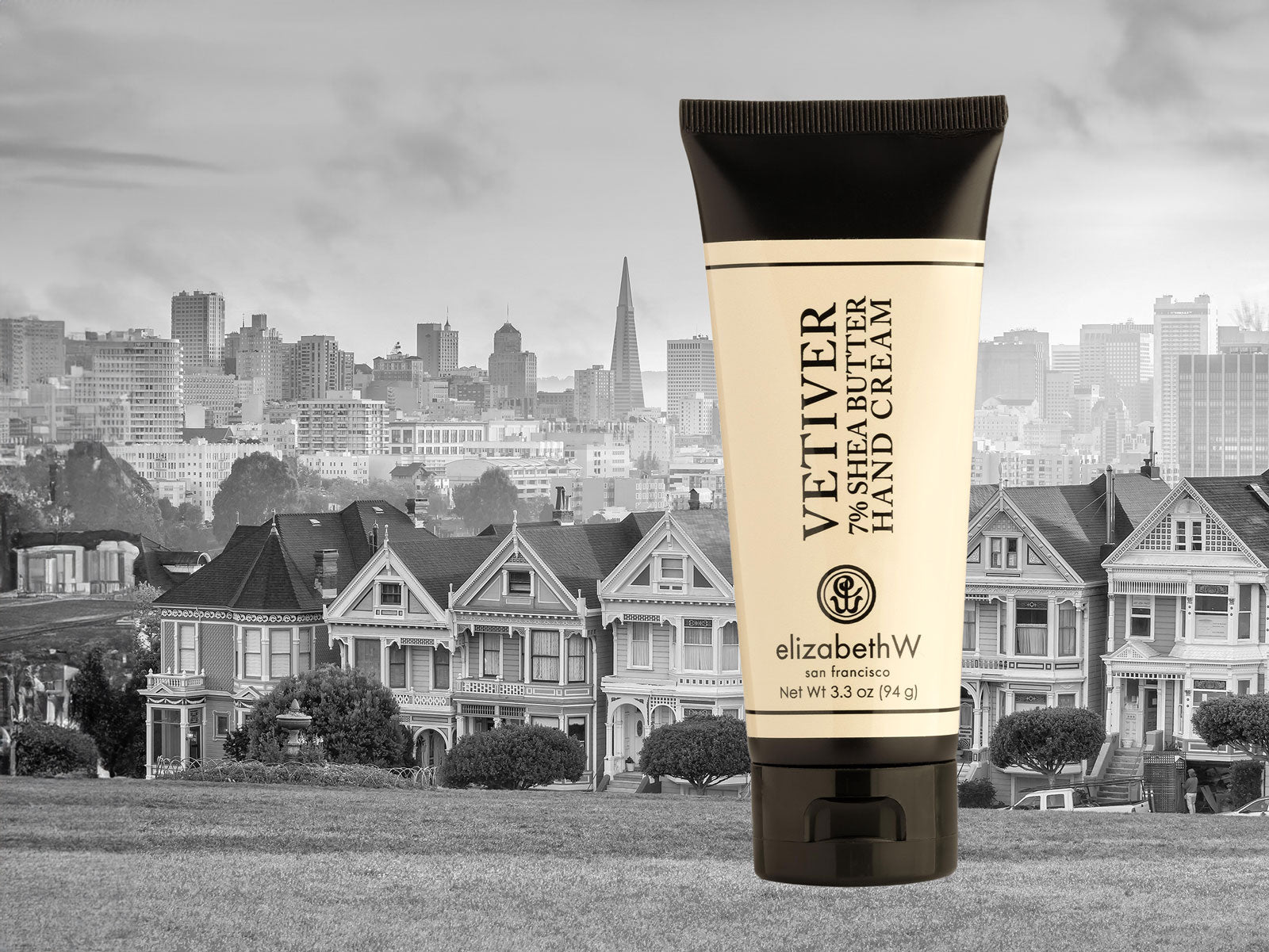 A bottle of elizabethW Vetiver Hand Cream over a row of San Francisco houses. 