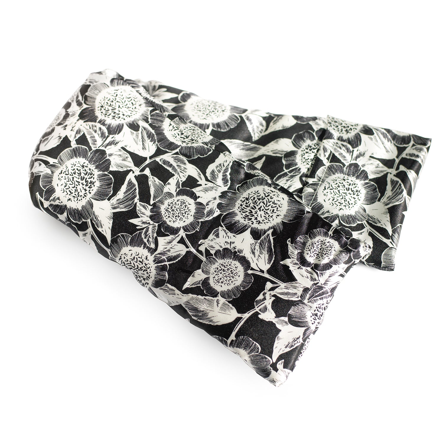 Neatly arranged against a plain white background, the elizabethW Carmel Daisy Hot/Cold Flaxseed Pack is covered in a silk casing displaying a black and white floral pattern and can be used as a heat pad or cold compress.
