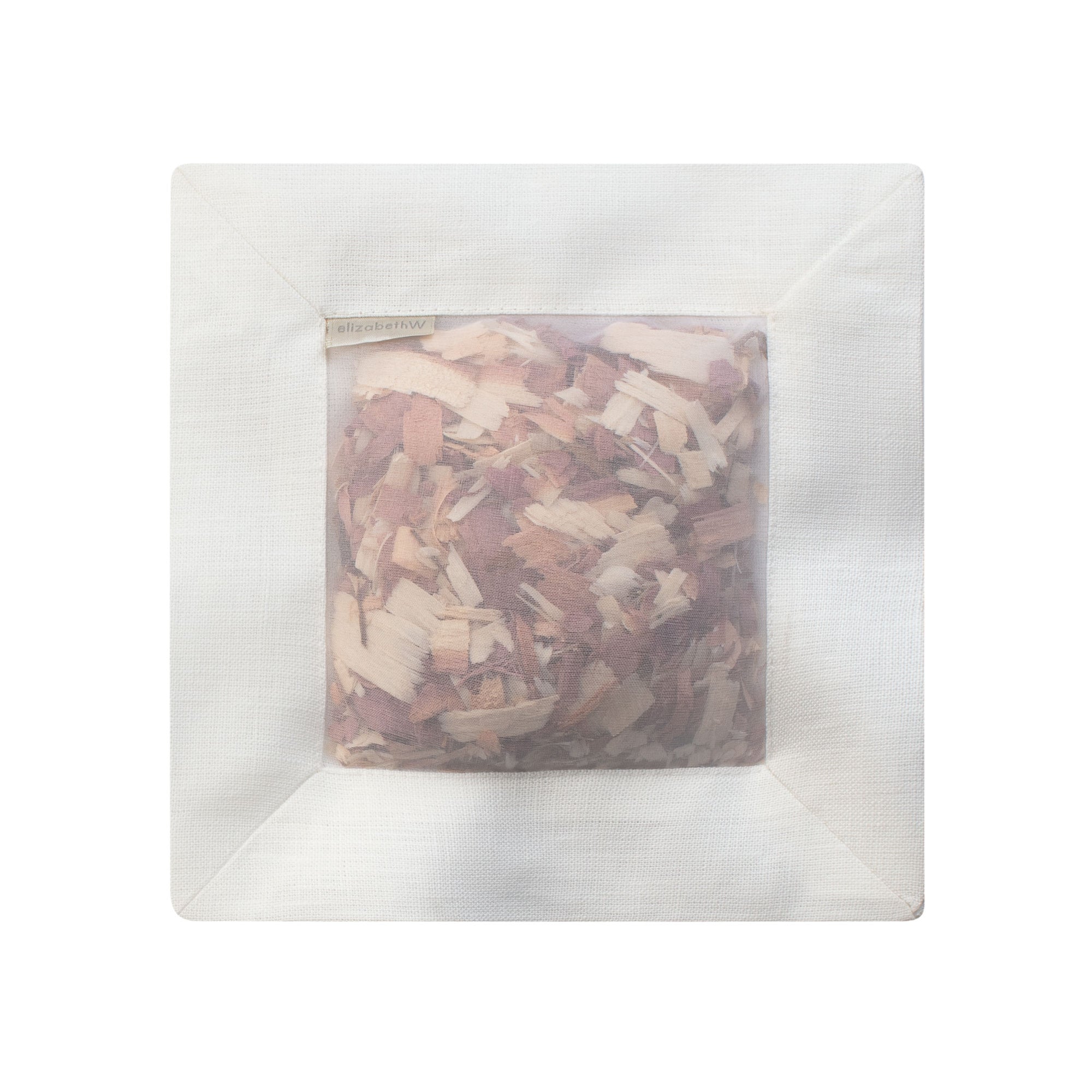 Cedar filled inside of an ivory colored square sachet with a transparent screen